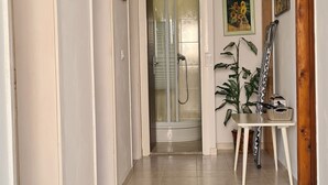 A hallway with tiled flooring, a wooden door, and a small table with a basket. - Apartment Next to the sea (Jelsa)