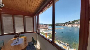 A room with a wooden ceiling, a large window with blinds, a round table with a vase, and a chair. - Apartment Next to the sea (Jelsa)