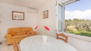 Um quarto com uma mesa redonda, um sofá e uma janela com vista para árvores e céu.