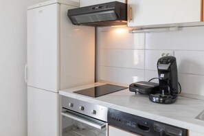 A compact kitchen with a built-in oven, a dishwasher, and a coffee maker on the countertop. - House MG (Skradin)