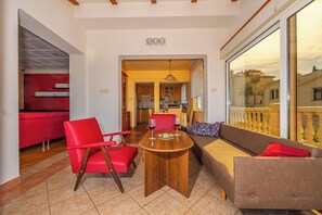 A modern living room with a wooden coffee table, red chairs, and a beige sofa. - Apartments Jarmila (Crikvenica)