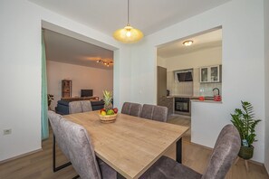 Un comedor moderno con una mesa de madera, sillas tapizadas en gris y un cuenco de frutas.