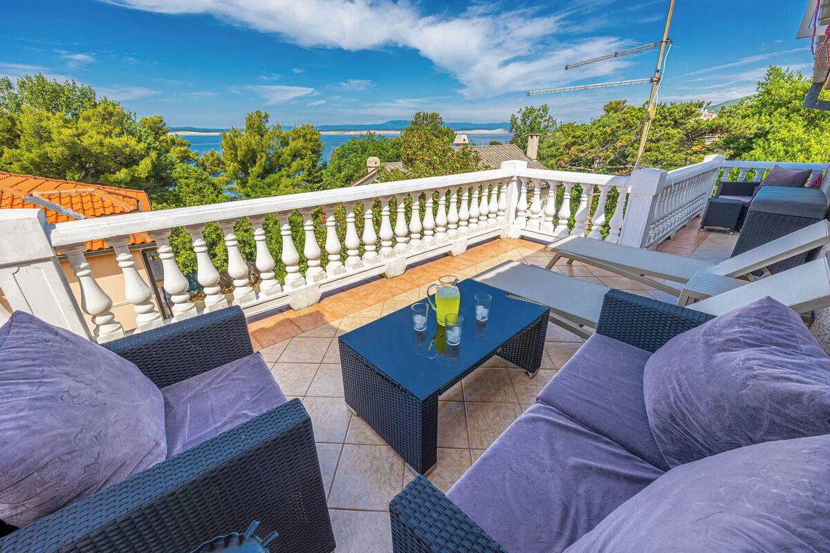 Une terrasse avec des meubles en osier, une table avec des boissons et une vue sur la mer.