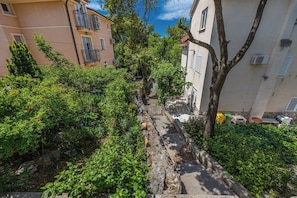 A narrow stone pathway flanked by lush greenery and residential buildings. - Apartments Jarmila (Crikvenica)
