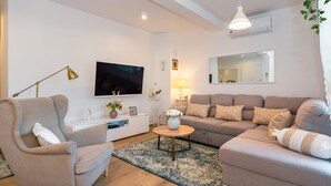 A living room with a sofa, armchair, TV, lamp, and a mirror on the wall. - Apartment Mia (Sibenik)