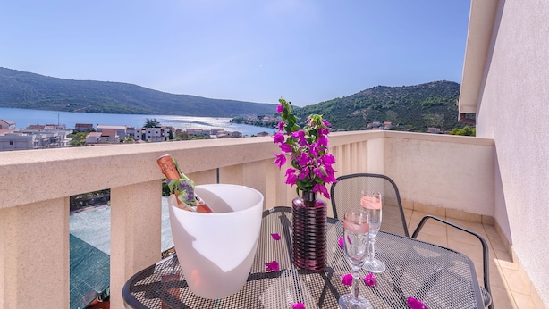 Ein Balkon mit Tisch für Zwei, einer Champagnerflasche und einem Blumenstrauß.