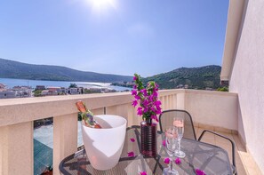 A balcony with a table set for two, a bottle of champagne, and a vase of flowers. - Apartment Karolina (Marina)