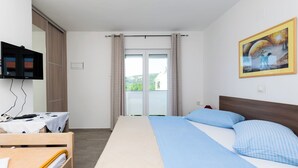 A hotel room with a bed, a desk, a television, and a window with curtains. - House Nenad (Lopar)