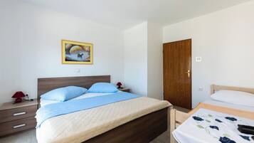 Quarto com uma cama grande, mesa de cabeceira com abajur, porta de madeira e um quadro na parede.