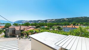 A residential area with houses, a clear sky, and mountains in the background. - House Nenad (Lopar)