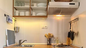 A compact kitchen with white cabinets, a wooden countertop, a built-in sink, and a small refrigerator. - Apartment Bosiljak (Jelsa)