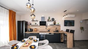 Een moderne keuken met een centraal eiland, zwarte apparaten en hanglampen.