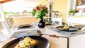 Een eettafel met een zwart bord eten, een vaas bloemen en een menukaart.