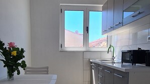 Une cuisine moderne avec un coin repas, une fenêtre et une vue sur un bâtiment aux toits rouges situé à l’extérieur.