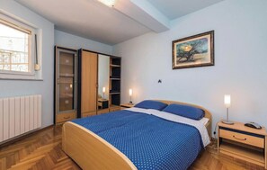 Ένα υπνοδωμάτιο με ένα κρεβάτι, κομοδίνα, μια ντουλάπα και έναν πίνακα στον τοίχο.