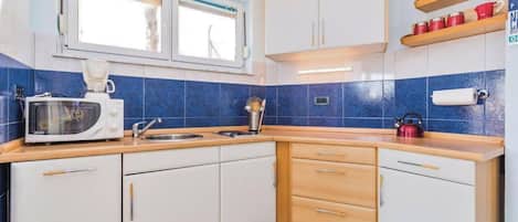 A compact kitchen with white cabinets, a microwave, a sink, and a checkered floor.