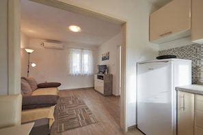 A compact living space with a kitchenette, a sofa, a small TV, and a refrigerator. - House Dvor (Seget)