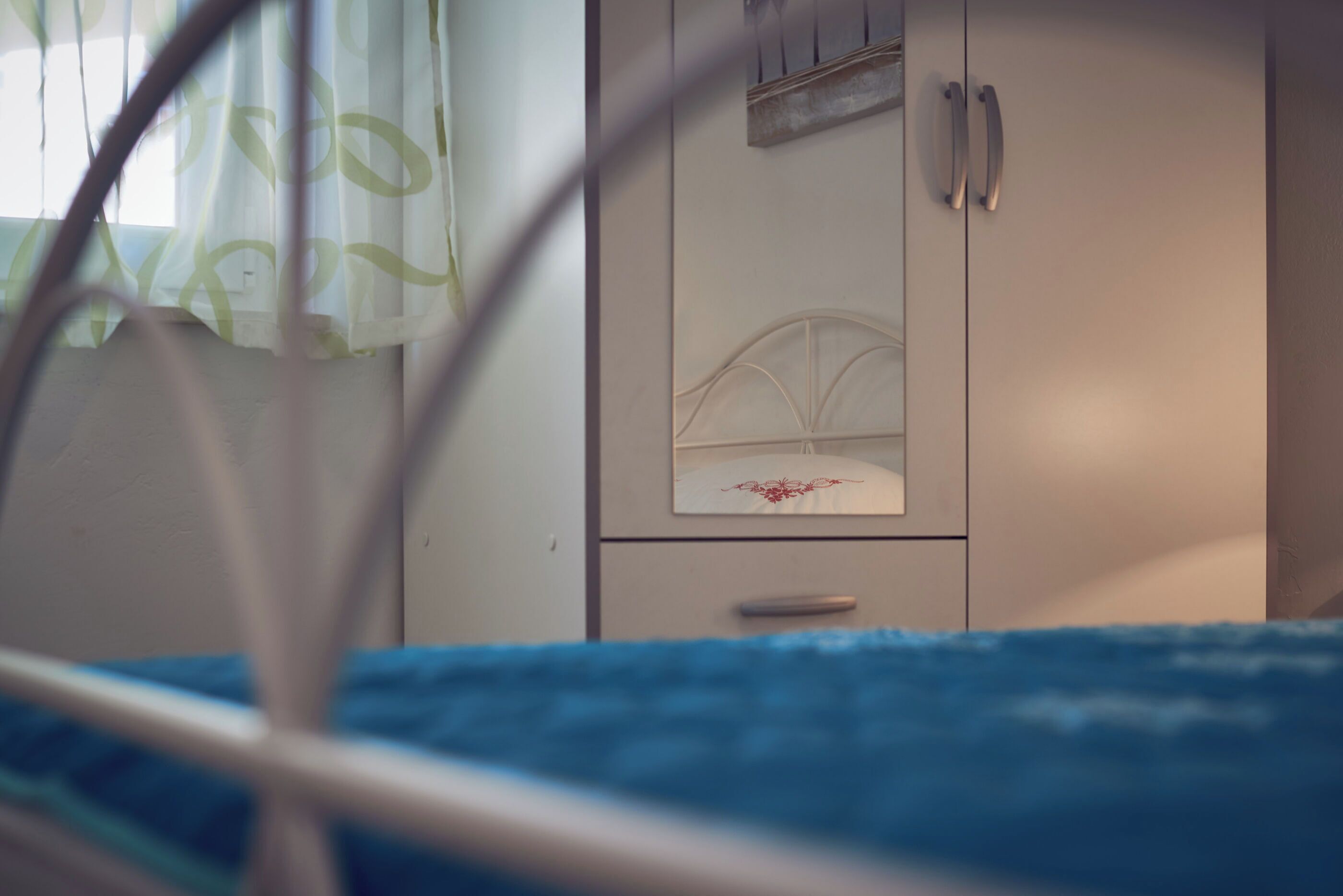 Een slaapkamer met een bed, een kledingkast en een raam met gordijnen.