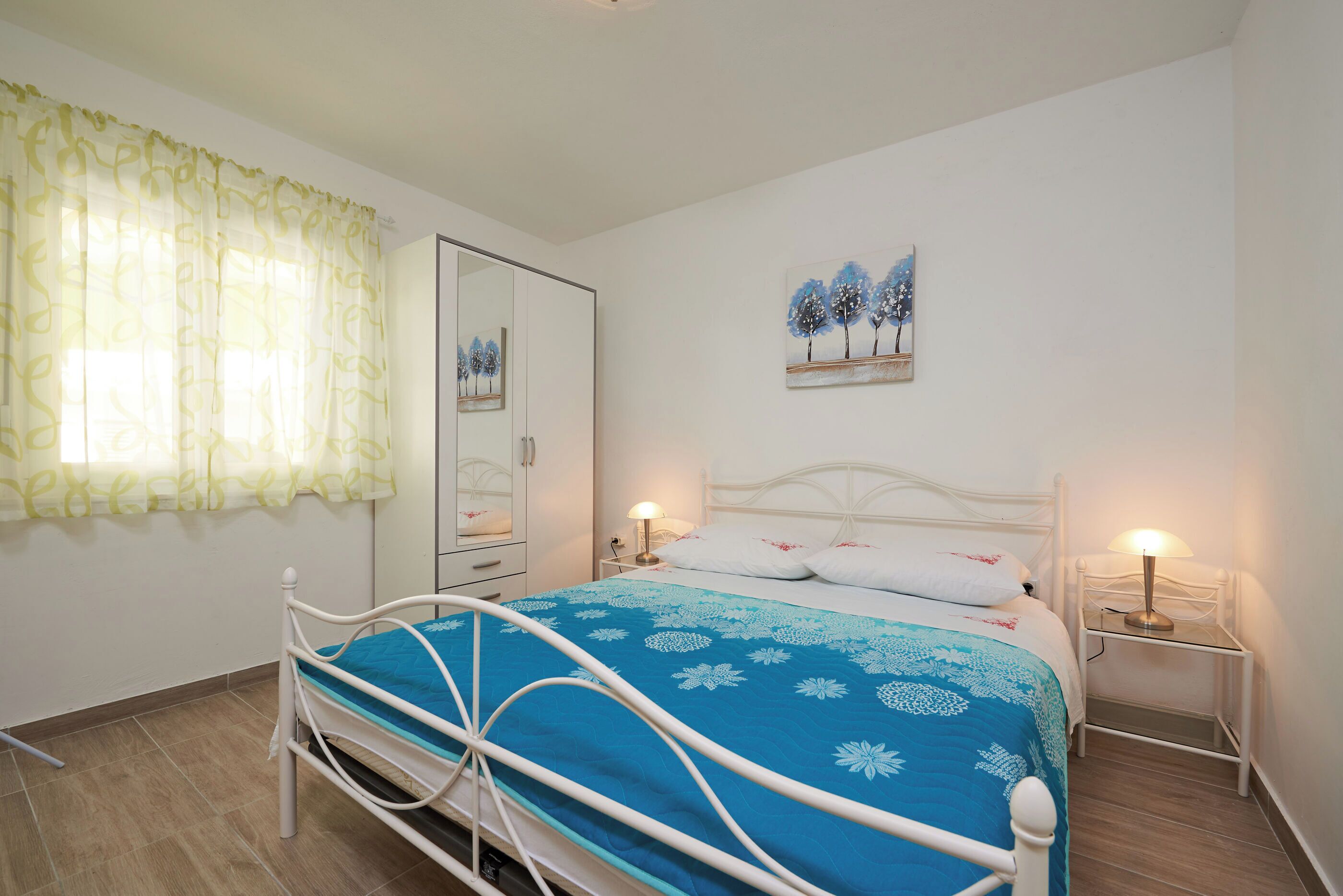 Una camera da letto con un letto, un comodino, uno specchio e un quadro appeso al muro.