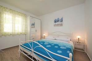 A bedroom with a bed, a nightstand, a mirror, and a painting on the wall. - House Dvor (Seget)