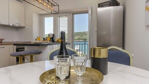 A modern kitchen with a dining area, a bottle of champagne, and two glasses on a tray. - Apartment Paradise (Sibenik)