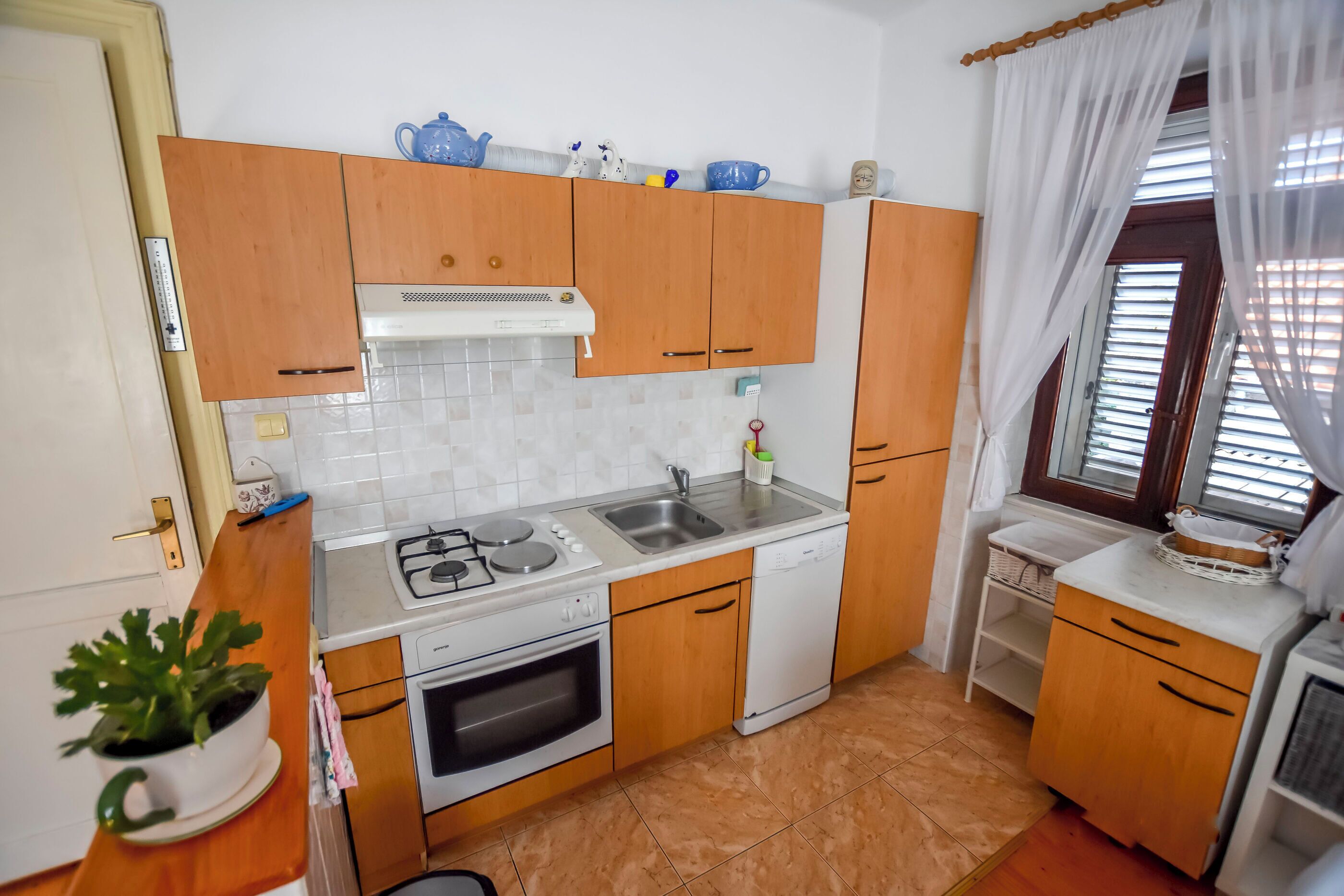 A compact kitchen with wooden cabinets, a gas stove, a dishwasher, and a sink.