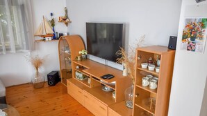 Ein modernes Wohnzimmer mit einem Holzkasten, einem Fernseher und Dekorationselementen.