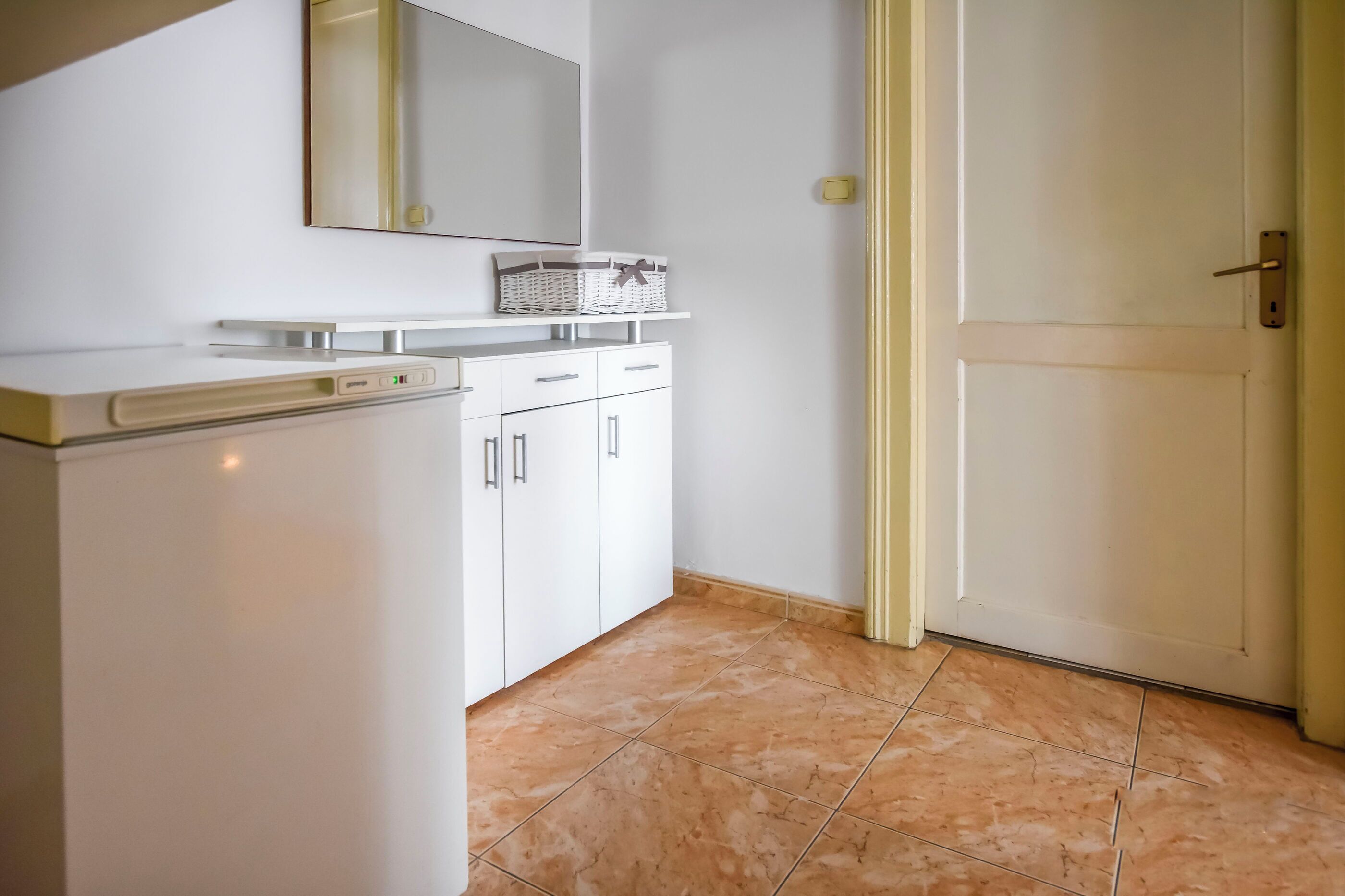 Una cocina con armarios blancos, una encimera y suelo de baldosas.