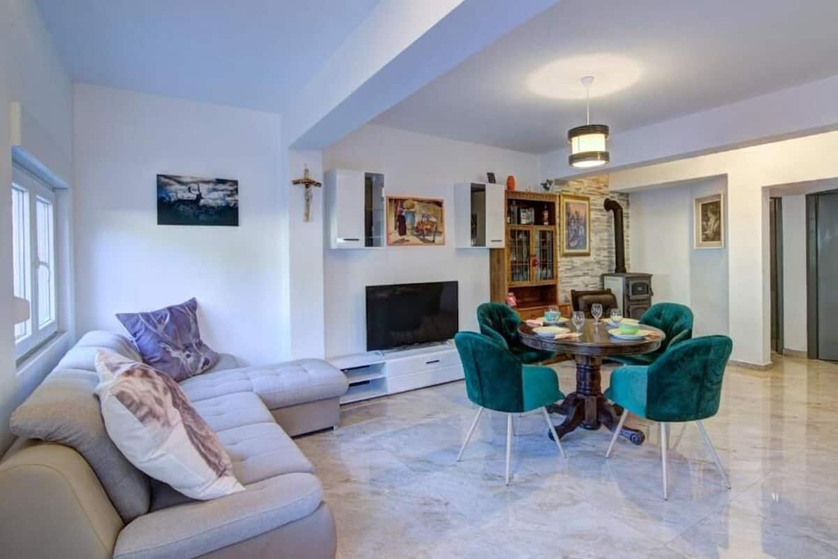 A living room with a sofa, a TV, a dining table with chairs, and a fireplace.