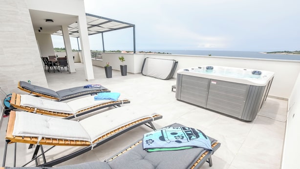 A rooftop terrace with lounge chairs, a hot tub, and a view of the sea. - Apartment Sea Heaven (Rogoznica)