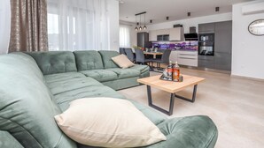 A modern living room with a sectional sofa, a wooden coffee table, and a dining area in the background. - Apartment Sea Heaven (Rogoznica)