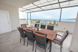 En balkon med et bord og stole, med udsigt over kysten.