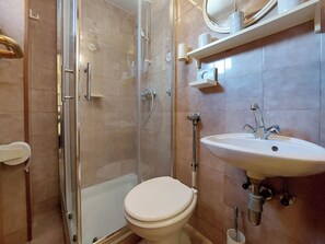 A bathroom with a glass-enclosed shower, a white toilet, and a sink with a mirror above it. - Apartments Vida (Novi Vinodolski)
