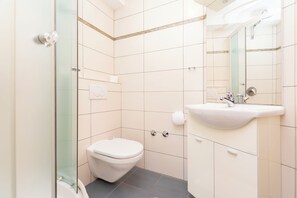 A bathroom with a toilet, sink, and glass shower enclosure. - Apartments Danijela (Dugi Rat)