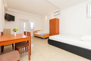 A bedroom with a bed, a wooden wardrobe, a bedside table, a TV mounted on the wall, and a window. - Apartments Danijela (Dugi Rat)