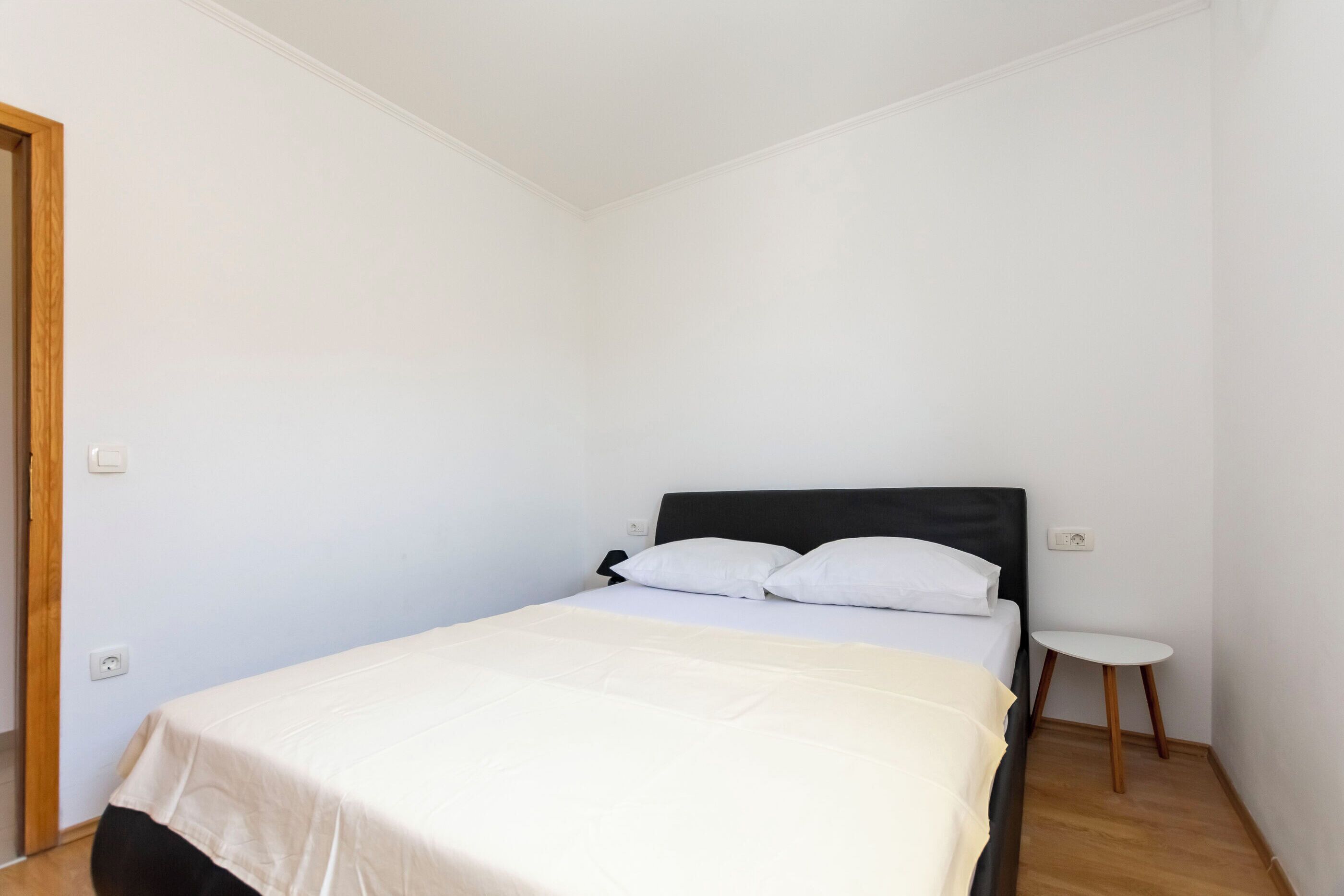 Una camera da letto piccola e ordinata, con un letto singolo, un comodino e una porta.