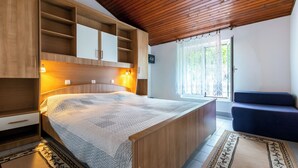 Une chambre avec un grand lit, des armoires en bois, une fenêtre avec des rideaux et un canapé bleu.