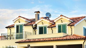 A two-story building with a tiled roof, green shutters, and a satellite dish. - Apartment Sunshine (Vodice)