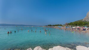 En travl strand med krystalklart turkis vand og klippeformationer.