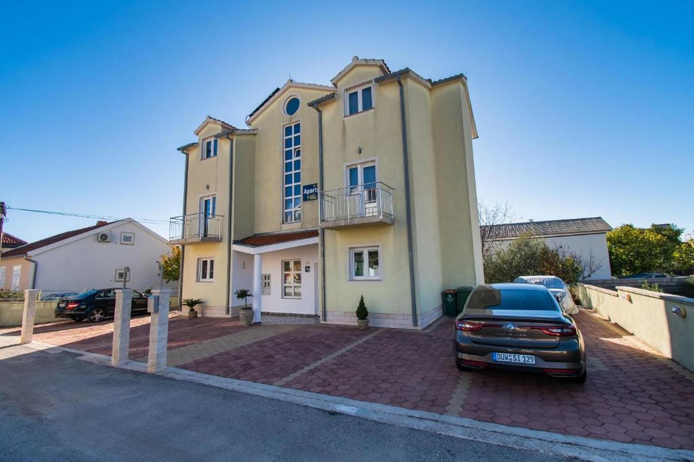 Un bâtiment à deux étages doté d’un balcon au deuxième étage, d’une petite entrée et d’une allée pavée.