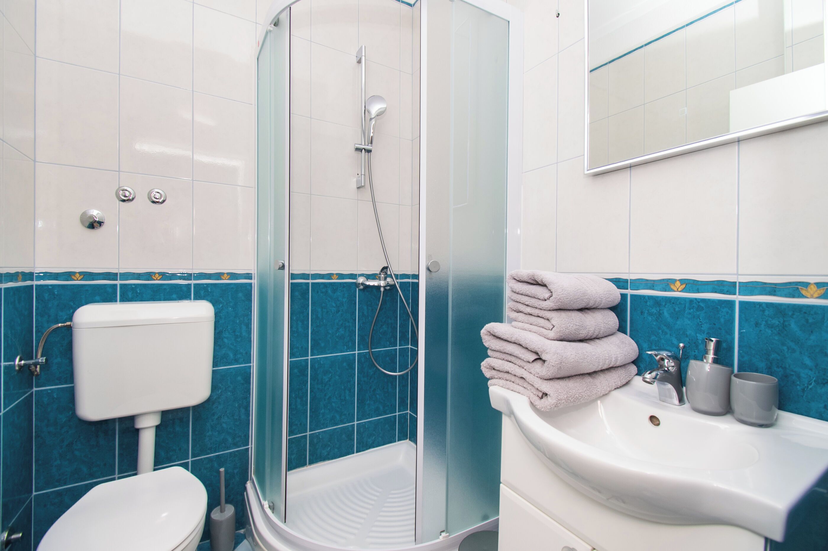 Une salle de bain avec une douche à parois de verre, un lavabo blanc doté de deux robinets et des toilettes.