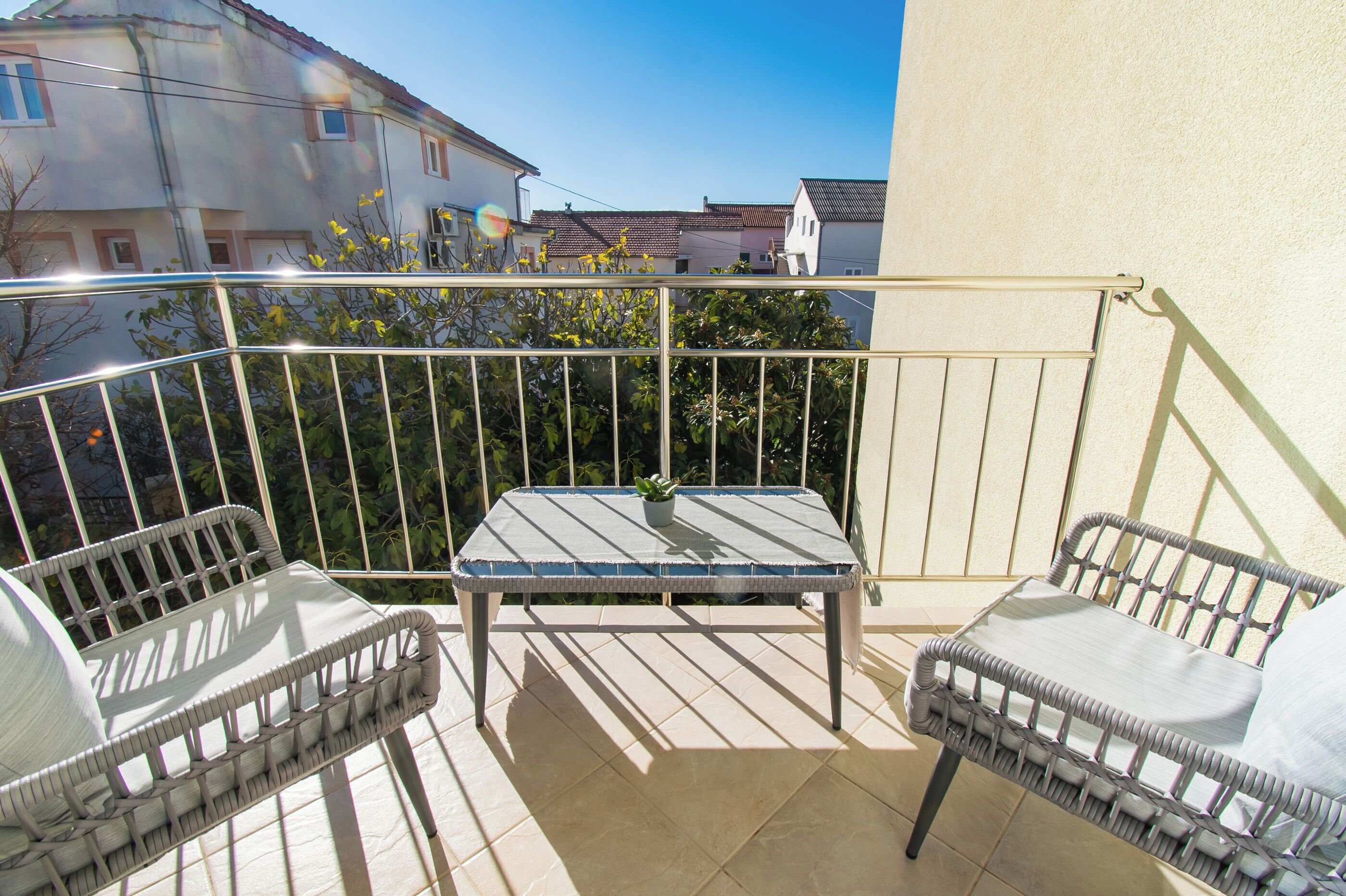 A balcony with two wicker chairs and a small table, featuring a potted plant.