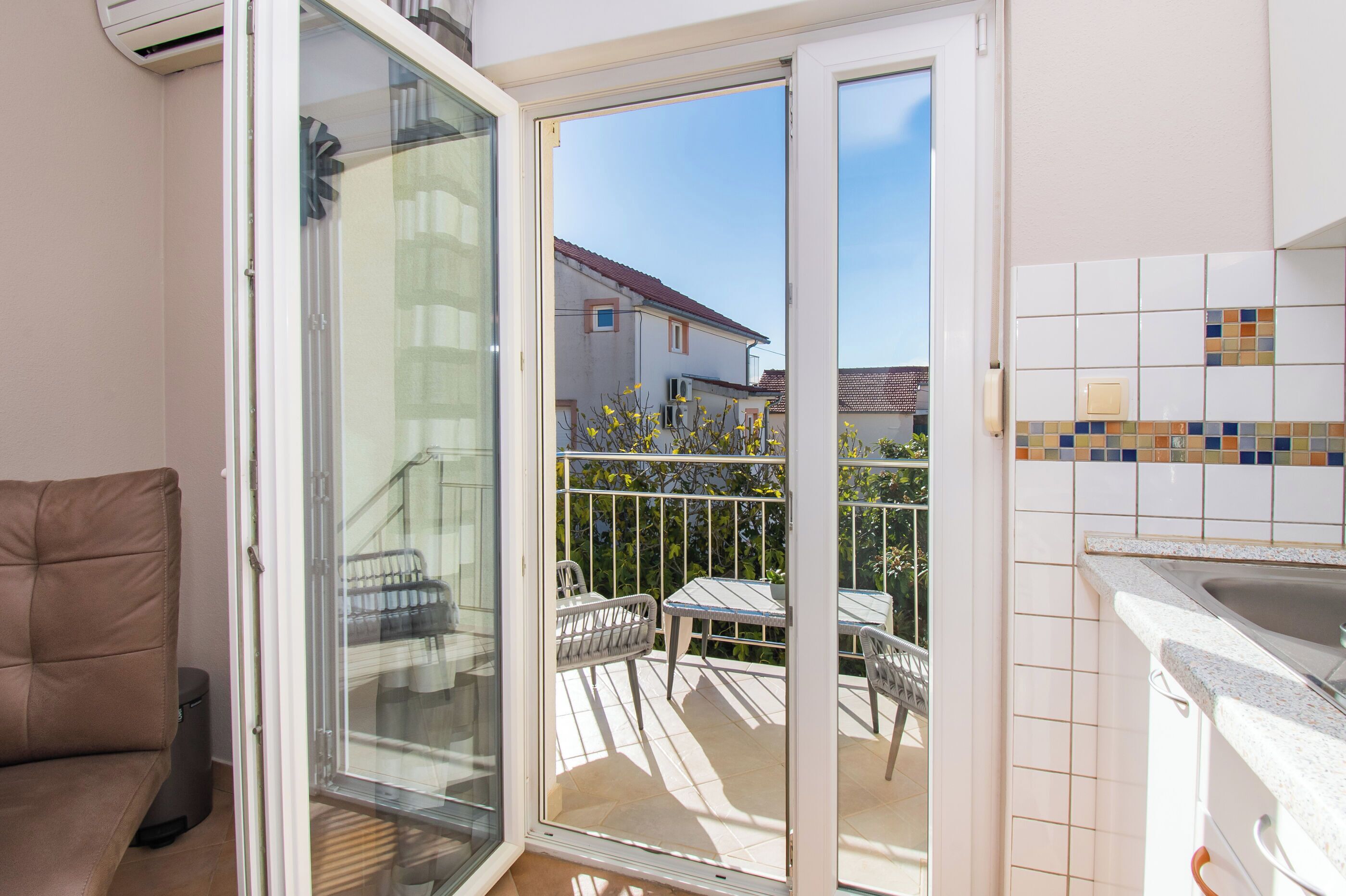 Un balcon avec une porte vitrée donnant sur une terrasse, une table à manger et des chaises.