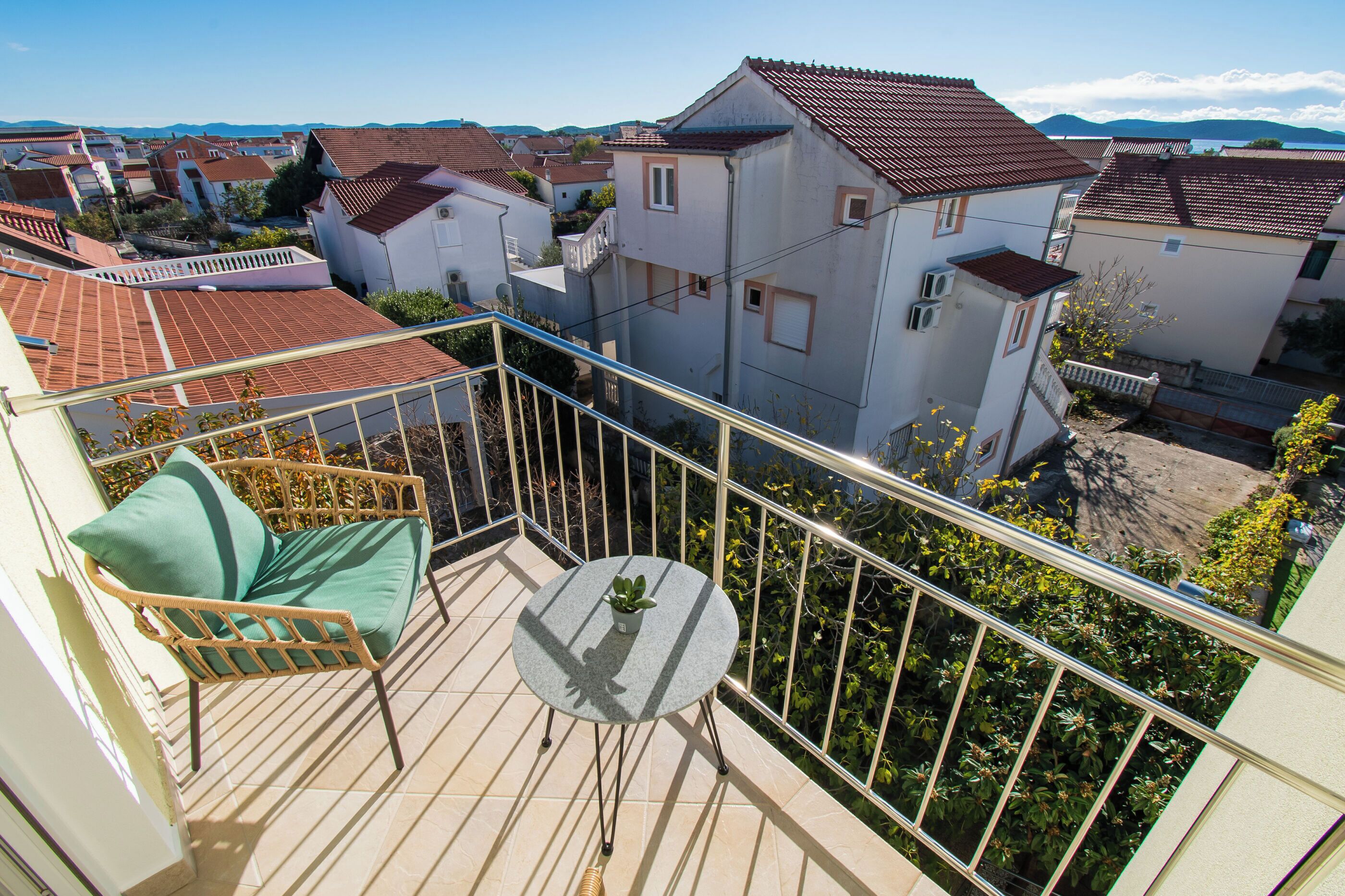 A balcony with a chair, a small table, and a potted plant.
