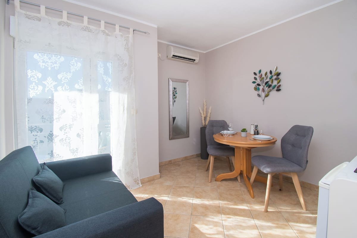 A room with a sofa, two chairs, a small round table, and a mirror on the wall.