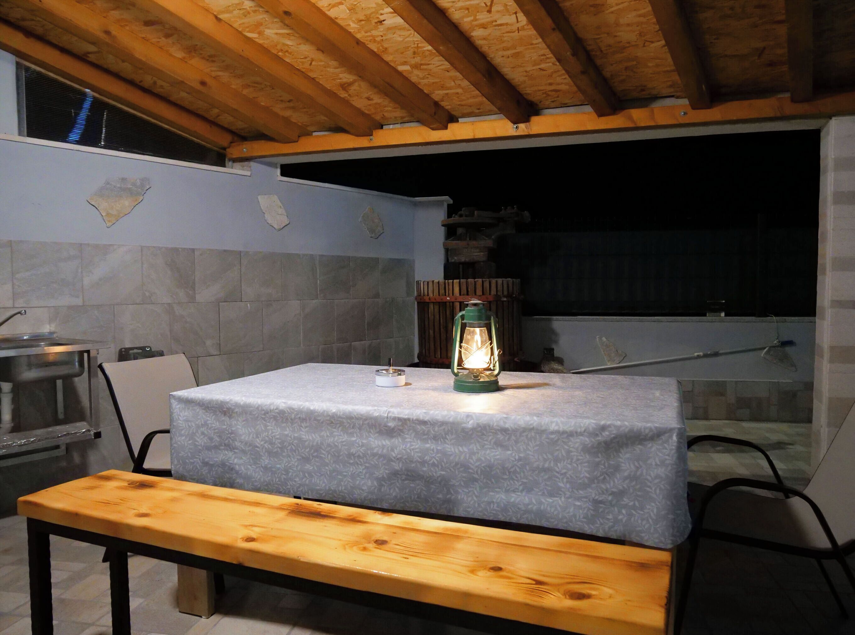 A kitchen with a table and bench, a lantern, and a window.