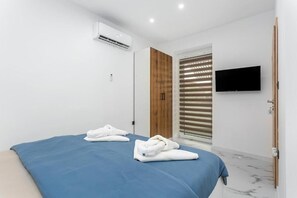 Ein modernes Hotelzimmer mit Bett, Wandfernseher und Klimaanlage.
