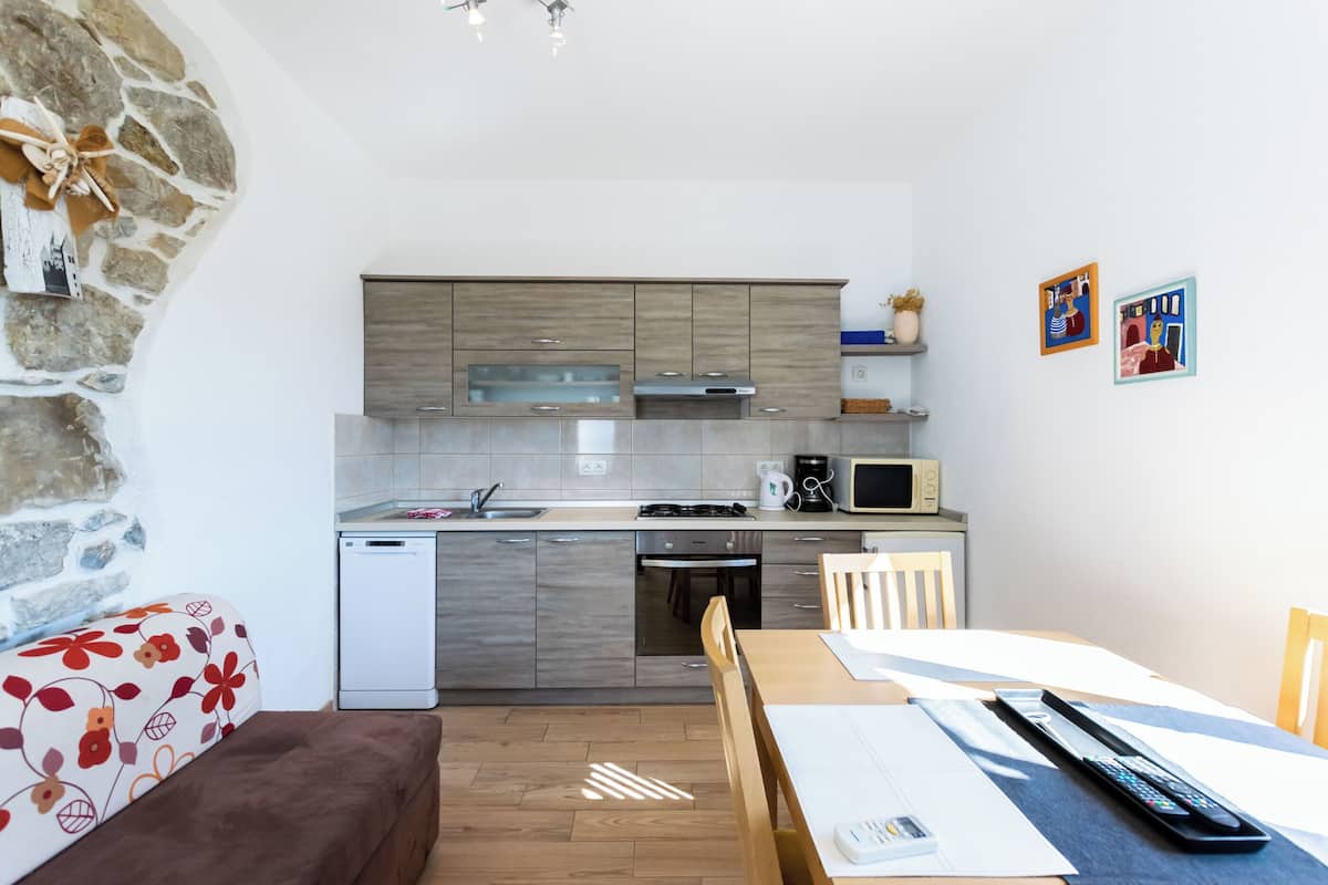 Een compacte keuken met moderne apparaten, een eethoek met een tafel en stoelen, en een stenen muur aan de zijkant.