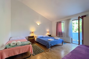 A hotel room with two beds, a window with curtains, and a view of greenery outside. - Apartments Franjo (Rab)