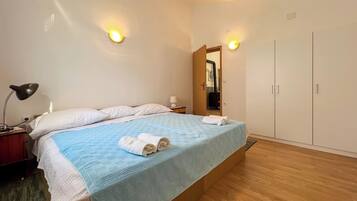 A bedroom with a bed, bedside lamps, a wardrobe, and a mirror.